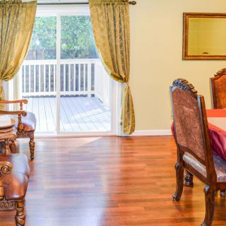 A cozy living and dining area featuring wooden floors, elegant furniture, and a sliding door leading to a deck.