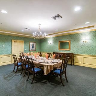 A formal dining room with a long table, chairs, and elegant decor.