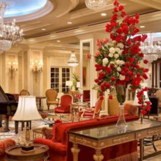 A luxurious living room with opulent decor, featuring chandeliers, a grand piano, and an elegant floral arrangement.