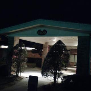 A dimly lit entrance to a building at night, framed by trees.