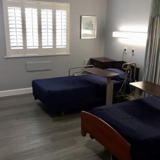 A sterile hospital room featuring two beds and medical equipment.