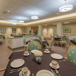 An elegantly set dining room with neatly arranged tables and chairs, featuring warm lighting.