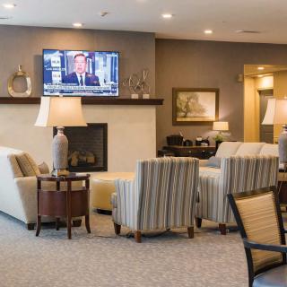 A cozy living room with comfortable seating, a fireplace, and a television mounted above.