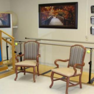 A physical therapy room with parallel bars and two chairs.