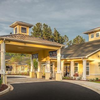 A yellow residential building with a covered entrance and landscaped surroundings.