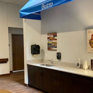 A small kitchenette area with a sink, counter, and blue awning in an office setting.