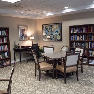 A cozy library room with bookshelves, a table, and chairs for studying.