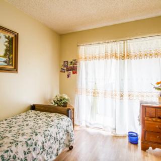 A cozy bedroom with a single bed, floral bedding, and natural light streaming through the curtains.