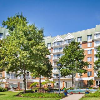 A residential apartment building surrounded by trees and a park-like outdoor area.