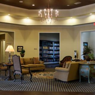 A cozy lobby area featuring comfortable seating, a chandelier, and a bookshelf.