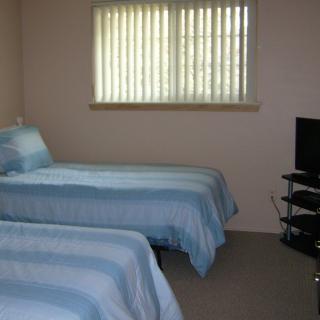 A cozy bedroom with twin beds and a television by the window.