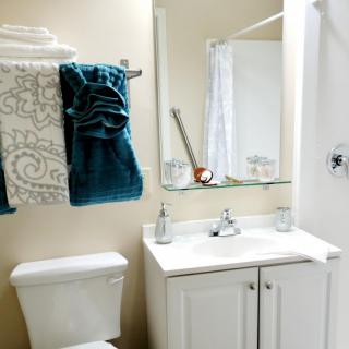 A neatly arranged bathroom with a sink, mirror, and towels.