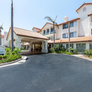 The welcoming entrance of a hotel featuring a Spanish-style architecture and landscaped surroundings.