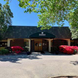 A pleasant building surrounded by vibrant flowers and greenery on a sunny day.