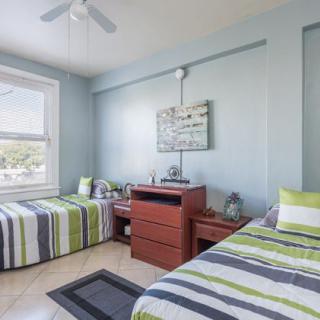 A modern bedroom with two twin beds featuring striped bedding and wooden furniture.