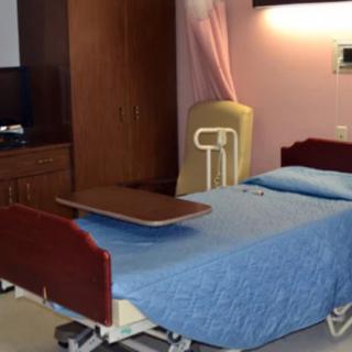 A hospital room with a single bed covered in a blue blanket.