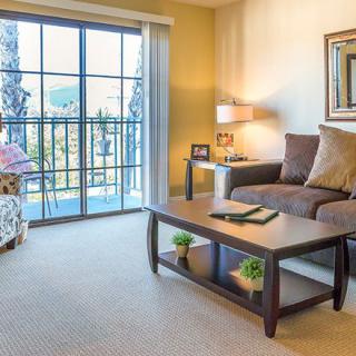 A cozy living room with a sofa, coffee table, and view through large windows.