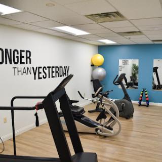 A well-equipped gym space featuring various exercise machines and motivational decor.