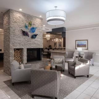 A modern hotel lobby with comfortable seating and a central fireplace.