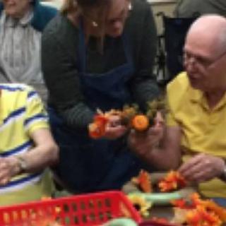 A group of people engaged in a flower arranging activity with assistance.