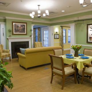 A cozy living and dining area with green walls, elegant furniture, and a welcoming atmosphere.