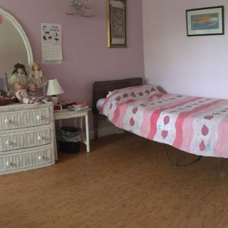 A cozy bedroom with pink walls, a neatly made bed, and classic furniture.