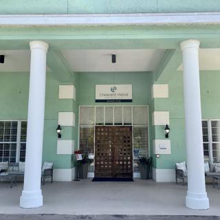 The front entrance of a building with a green exterior and large columns.