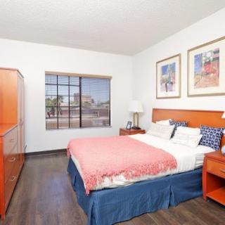 A cozy and vibrant hotel bedroom featuring orange accents, modern furniture, and a sunny window view.