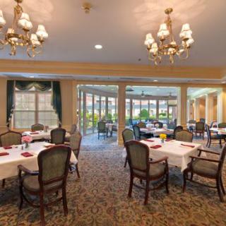 An elegant dining area with tables and chairs, adorned with chandeliers and large windows.