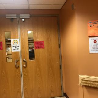 Entrance to a facility with visible signage and wooden double doors.