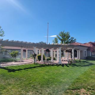 A sunny day view of a house with a well-maintained lawn and garden.