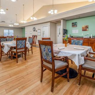 A clean and well-lit dining area with wooden floors and neatly arranged tables and chairs.