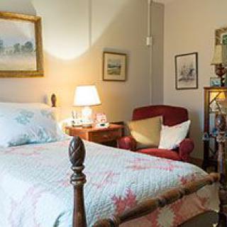 Cozy bedroom with a quilted bed, warm lighting, and classic decor.