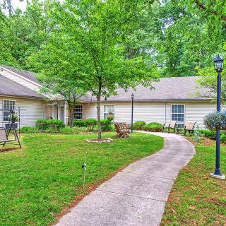 A scenic view of a house with a curving pathway surrounded by a well-maintained lawn and trees.