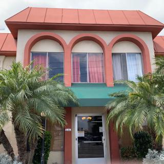 A building exterior with palm trees and a green awning.