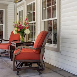 A cozy patio setup with red-cushioned chairs and a table adorned with flowers.