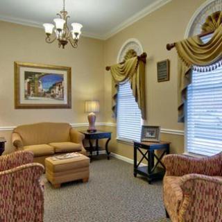 A traditionally decorated living room featuring a sofa, chairs, and elegant curtains.