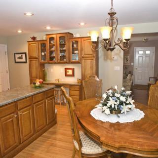 A cozy kitchen and dining area featuring wooden cabinets, a round dining table with a floral centerpiece, and a chandelier.