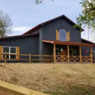 A rustic barn with a wooden exterior and surrounding fence.