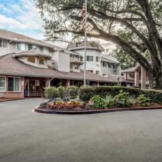 A residential building with a circular driveway and lush landscaping.