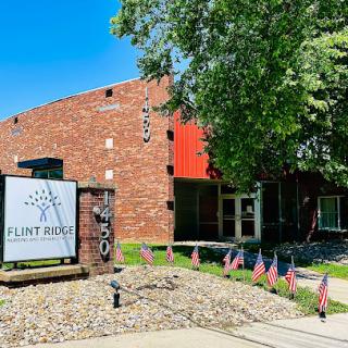 A community center with a modern design, featuring red brick and surrounded by flags.