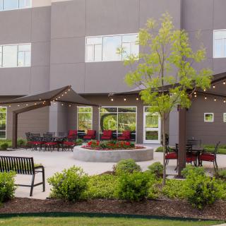 A modern outdoor patio area with seating, landscaping, and string lights.
