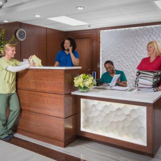 Employees at a reception desk in a medical office setting.