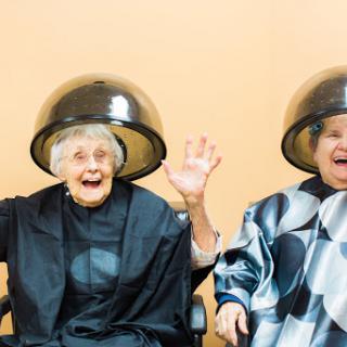 Two joyful elderly women enjoying a fun moment at the hair salon.