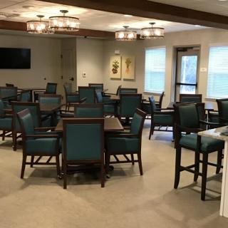 A well-furnished dining room with several tables and chairs arranged neatly under elegant lighting.