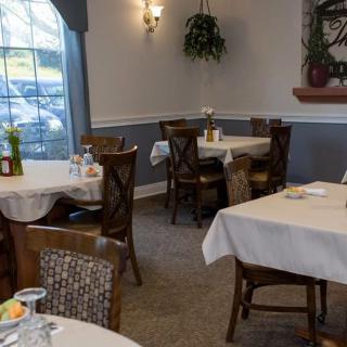 A cozy restaurant interior with neatly arranged tables and chairs, featuring warm lighting and decorative elements.