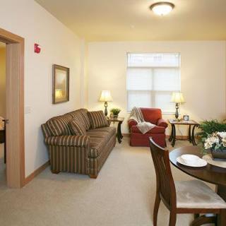 A cozy living room with a sofa, armchair, and dining table.