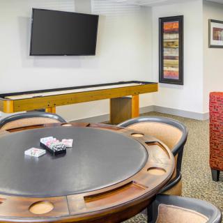 A well-furnished game room featuring a poker table, shuffleboard, and a television.