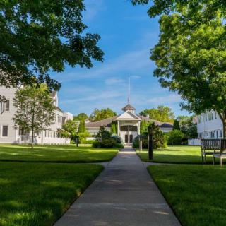 A path leading to a building surrounded by trees and greenery on a sunny day.