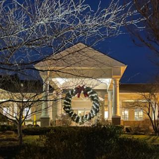 A beautifully decorated building at night featuring a large festive wreath.